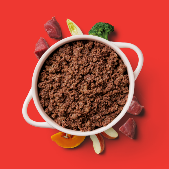 A pot of Gently Steamed Beef 395g with veggies and meat chunks on a red background.
