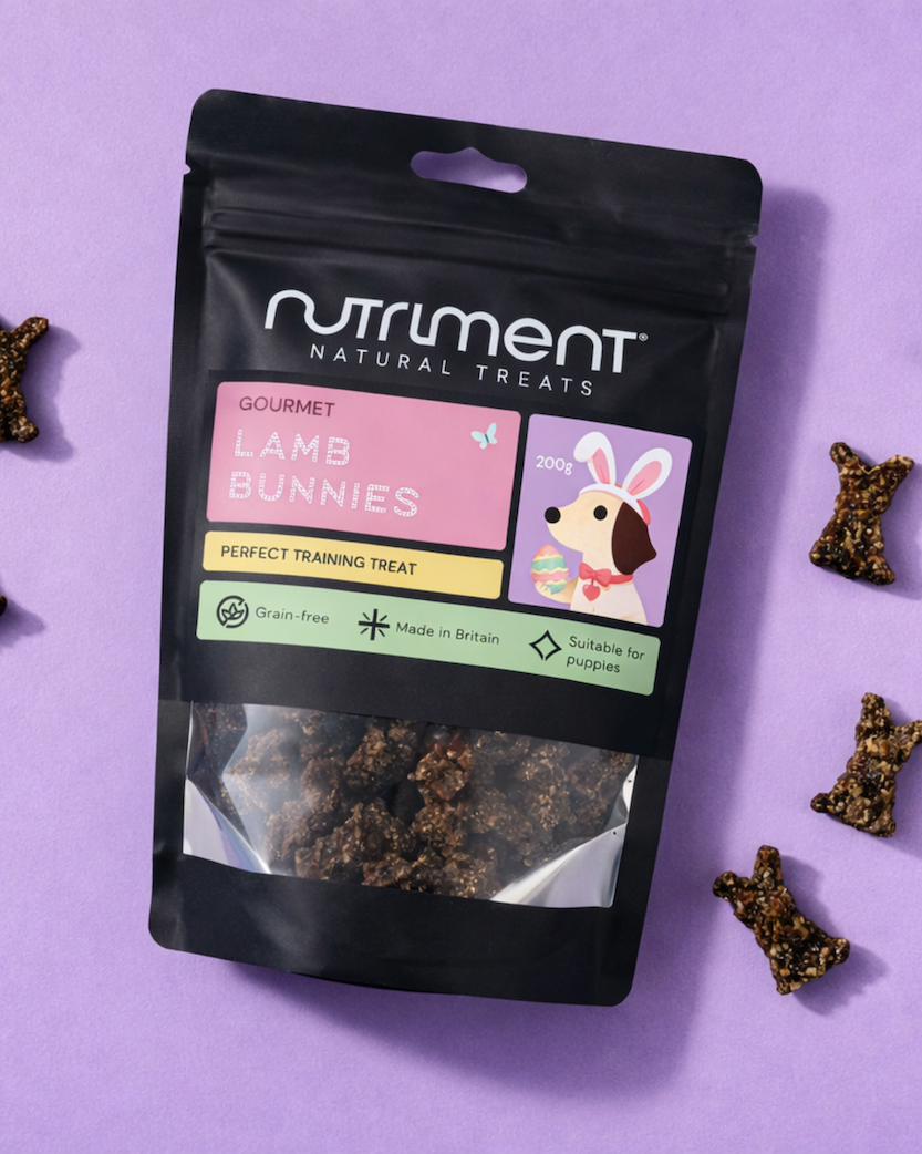 A bag of Nutriment Lamb Bunnies dog treats on a purple background with treats scattered around.